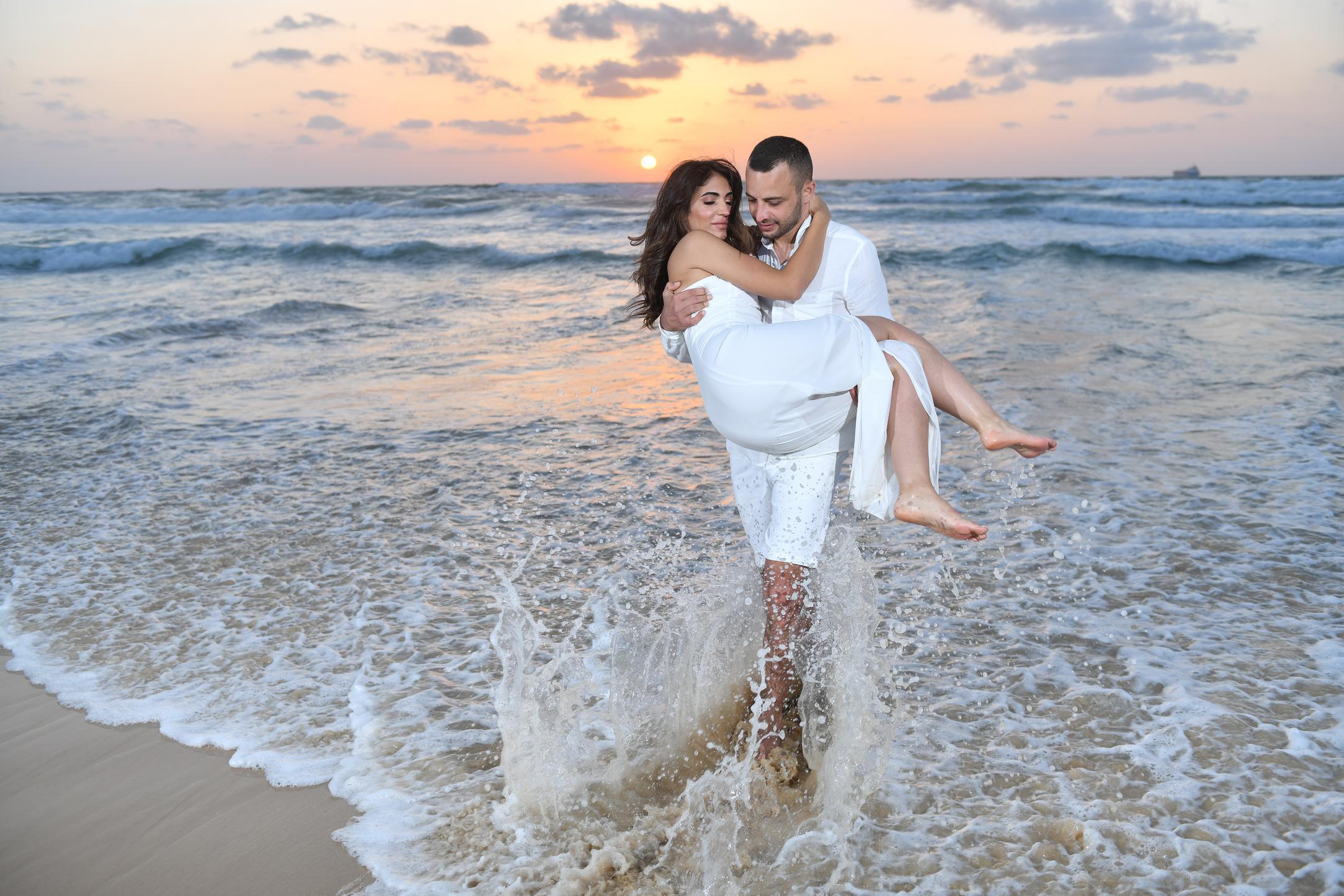 הזוג בטיול רומנטי בחוף בשעת השקיעה - רגע חד פעמי לזוג